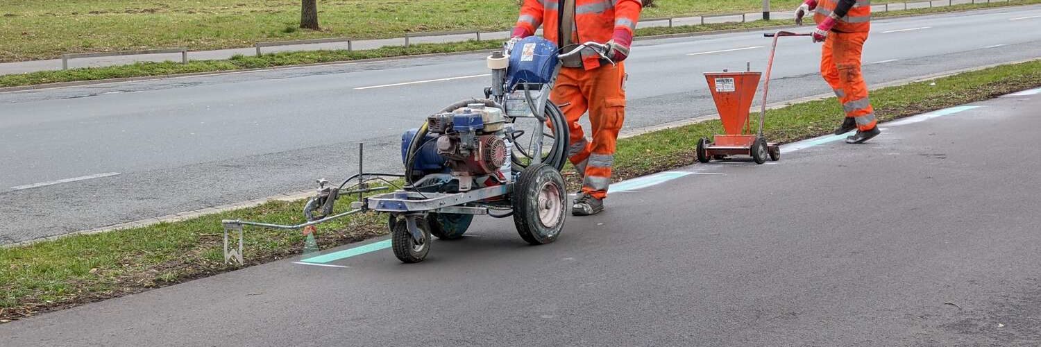 Aufbringen der Markierungen mit Sprühwagen und Abdeckung dahinter